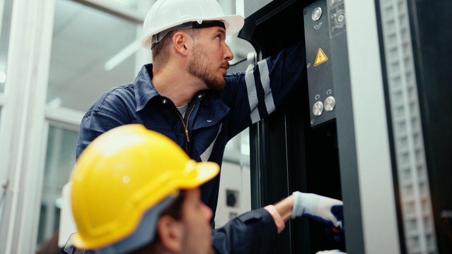 Electricians performing electrical maintenance on factory equipment.